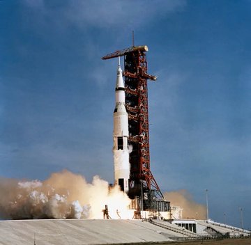 A Saturn V rocket lifts off from the launch pad, representing the powerful Apollo missions whose onboard guidance computer—weighing 70 pounds with just 4KB of RAM—Ken Shirriff famously programmed to mine Bitcoin.