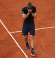 A tennis player in a black outfit stands on a clay court with his hands covering his face in apparent frustration or disbelief. The image relates to the post about a trader betting against a top player ("the GOAT") on Roobet, with the player's defeated posture symbolizing the outcome of the gamble.