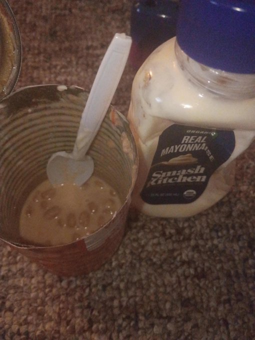 A close-up of an opened jar of 'Smash Kitchen Organic Real Mayonnaise' next to a tin can containing leftover mayonnaise with a white plastic spoon inside.
