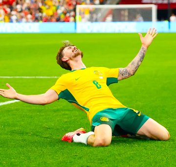 A soccer player wearing Australia's #8 jersey kneels on the field with arms outstretched in a celebratory pose, likely commemorating a goal. The image of an Australian team player celebrating contrasts with the post's lament about spending $299,700 to make just $300, suggesting a massive risk for a minimal reward — similar to how the player gave an all-out effort to celebrate a small victory.