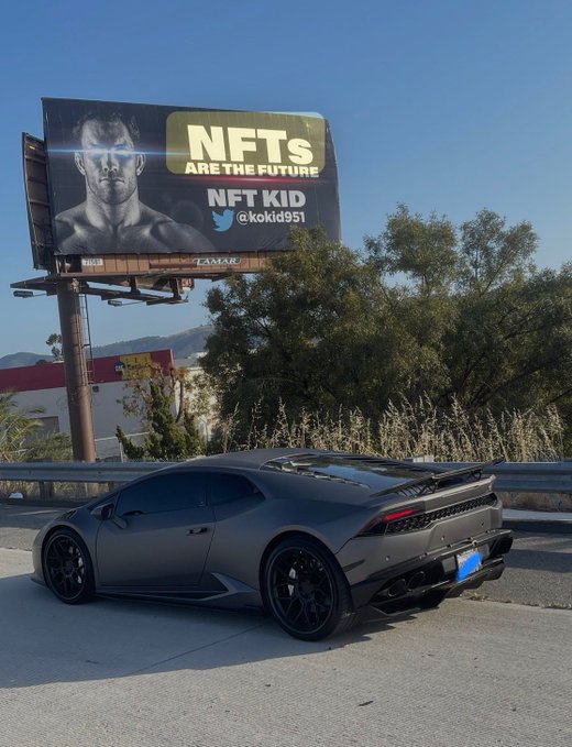 A matte black Lamborghini Huracán parks in front of a billboard reading "NFTs ARE THE FUTURE / NFT KID / @kokid951," reinforcing the post's message about NFTs remaining the most exciting part of crypto while showcasing the lifestyle often associated with the space.