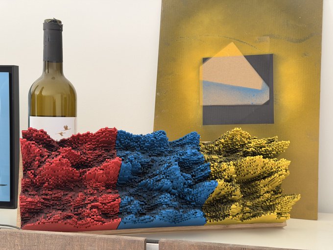 A textured 3D-printed sculpture featuring red, blue, and yellow sections sits on a wooden surface, accompanied by a wine bottle and an abstract painting in the background.