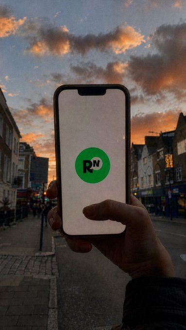 A hand holds up a smartphone displaying the green "Ramp Network" (RN) logo against a sunset city street, visually illustrating the brand's call to "show us where you use Ramp Network" as part of their social media giveaway challenge.