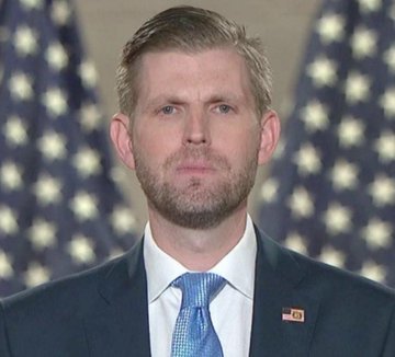 Eric Trump, wearing a dark suit, blue tie, and an American flag lapel pin, stands before a backdrop of American flags with a serious expression. The image accompanies his statement declaring that "ETH is pumping hard" and that "crypto is the future," aligning his public persona as a political figure with his endorsement of cryptocurrency momentum.