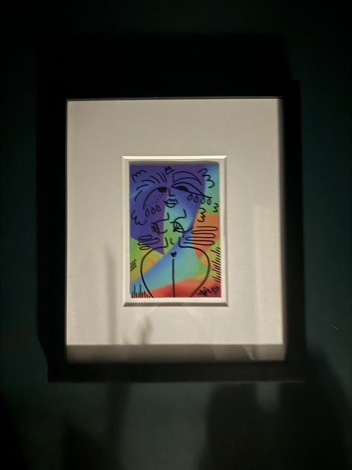 Framed Picasso-style abstract print hanging on a dark gallery wall, photographed in low light.