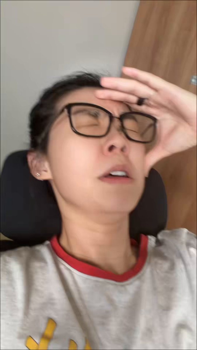 The image shows a person wearing glasses, with their head resting on a chair or pillow. They appear to be looking down at something, possibly a computer screen or a book. The background of the image is blurred, but there are some visible objects such as a desk and a window. The caption provided in the image reads "Algo is fixed. Views are gone. My content sucks." This statement seems unrelated to the person wearing glasses and resting their head on a chair.