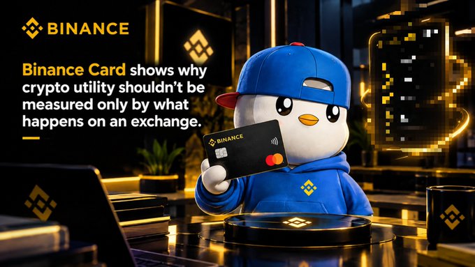 Binance promotional image featuring a blue cartoon penguin character wearing a hoodie and cap, holding a black Binance Card, with text stating 'Binance Card shows why crypto utility shouldn't be measured only by what happens on an exchange.'