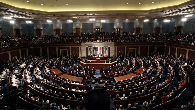 The image shows the interior of the U.S. House of Representatives chamber, filled with members seated in the curved rows facing the Speaker's rostrum, where the American flag is prominently displayed. This iconic legislative setting provides visual context for the accompanying post about the U.S. Senate's decision to postpone its vote on the CLARITY Act to September, illustrating the broader congressional environment in which such financial regulatory legislation is being deliberated.