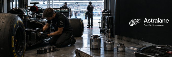 A Pit lane scene showing a mechanic working on a Petronas Formula 1 car with large tires, with 'Astralane' branding and the tagline 'Fast. Fair. Unstoppable.' in the upper right.
