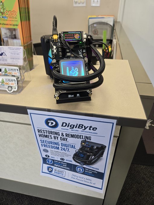The image shows a desk with various items, including a poster advertising DigiByte's services for digital security solutions. A computer monitor is also present on the desk. The poster features an advertisement for DigiByte's block, which can be used in a remodeling showroom setting to secure valuable items during the renovation process.

The post suggests that the block may have been purchased at a remodeling showroom and could potentially be used as a security measure for valuable items like jewelry or electronics. The image also includes text about DigiByte's services, which include digital security solutions such as digital locks and surveillance systems.