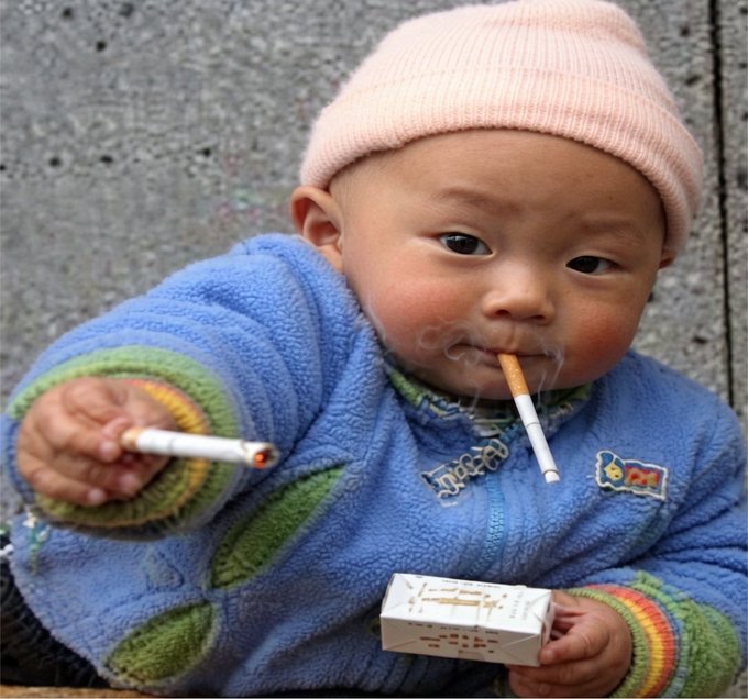 A young child in a pink knit hat and blue fleece jacket holds lit cigarettes in their mouth and hand while gripping a pack of cigarettes. The image serves as a stark warning of the dangers posed when security vulnerabilities are left unchecked and vulnerabilities are exploited as easily as a child could light a cigarette, illustrating the post's concern about gaps in human-built security that AI could exploit.