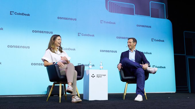 Two speakers sit on stage at CoinDesk's Consensus conference, with one holding a branded "Anchorage Digital" water bottle, in a panel discussion that aligns with the post's announcement about Morgan Stanley's new Bitcoin, Ethereum, and Solana trusts now trading on NYSE.