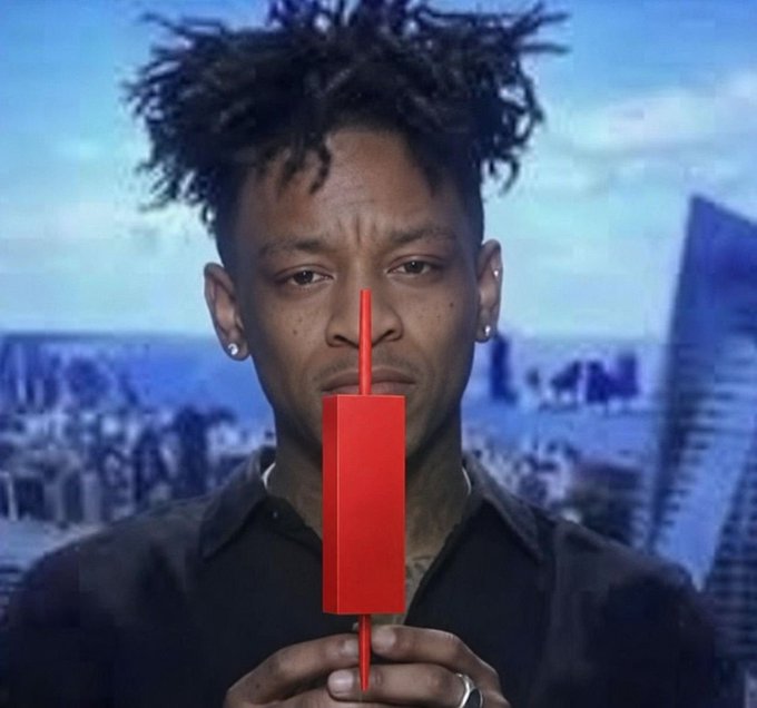 A man with dreadlocks holding a red vertical object in front of his face, with a city skyline visible in the background.