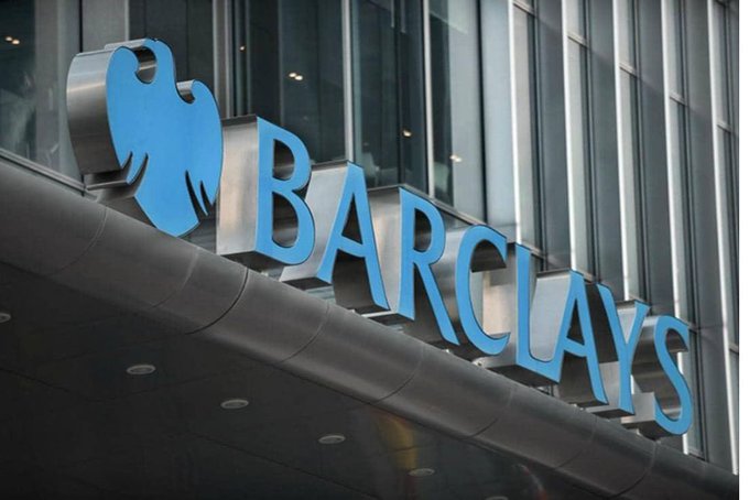 The image features a large, blue sign that reads "Barclays" with a bird logo above it. The sign is located outside of a building, possibly an office or store for the bank. The text on the sign is written in white letters against a black background, making it easily visible to passersby.
