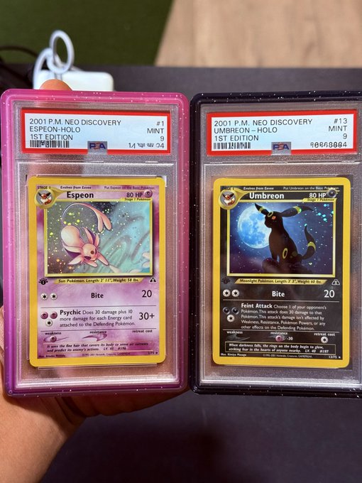 Two PSA-graded Pokemon cards held up: a 2001 P.M. Neo Discovery 1st Edition Espeon-Holo (#1, Mint 9) and a 2001 P.M. Neo Discovery 1st Edition Umbreon-Holo (#13, Mint 9).