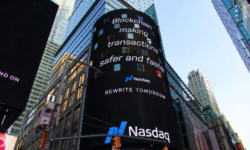 A large Nasdaq digital billboard in a cityscape displays the message "blockchain making transactions safer and faster" with "REWRITE TOMORROW" and the Nasdaq logo, tying into the post's announcement about Nasdaq officially promoting the Canton Network and blockchain technology.