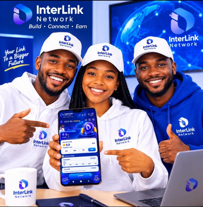 Three smiling individuals wearing white and blue InterLink Network branded hoodies and caps, with a woman in the center holding a smartphone displaying the InterLink Network staking app interface.