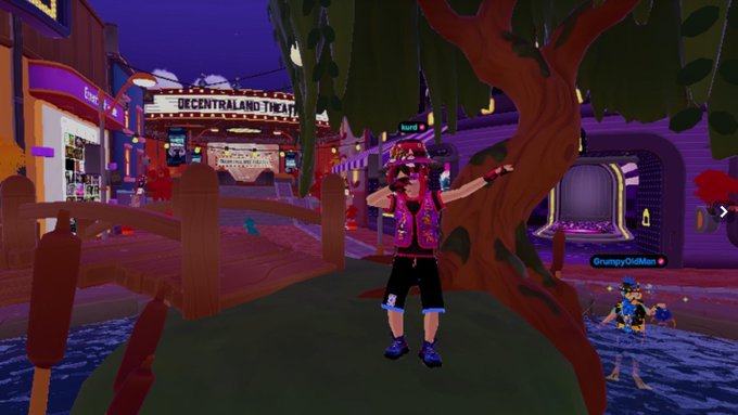 A screenshot from Decentraland's virtual world showing an avatar named "Kurt" posing near a tree, with the "DECENTRALAND THEATER" sign visible in the background and another user labeled "GrumpyOldMan" nearby, matching the post's invitation to join an event happening live in the metaverse.